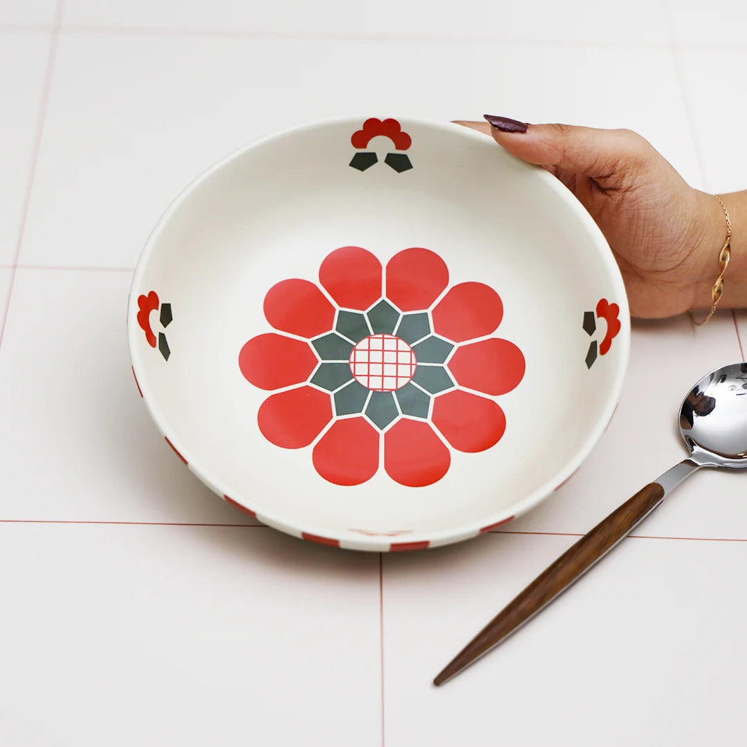 A hand holding red flowered ceramic bowl | pasta plate